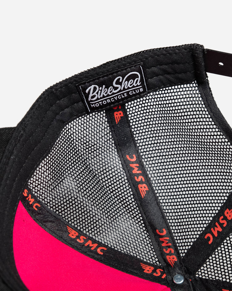 A black snapback baseball hat with a colorful patch on the front featuring a cartoonish motorcycle skull and bike shed logo - interior detail