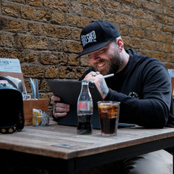 A black snapback baseball hat with 'Bike Shed Moto Co.' logo embroidered on the front.
