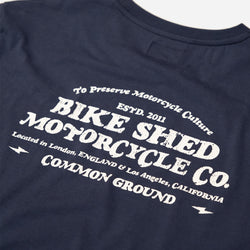 A navy-colored T-shirt with 'BIKE SHED MOTORCYCLE CO. COMMON GROUND' printed on the back.