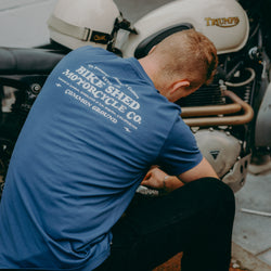 A navy-colored T-shirt with 'BIKE SHED MOTORCYCLE CO. COMMON GROUND' printed on the back.