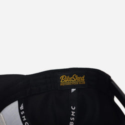 A black snapback baseball hat with 'Bike Shed Moto Co.' logo inner detail