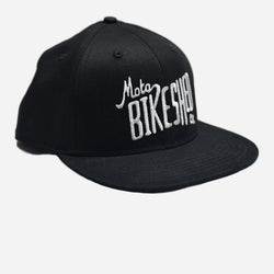 A black snapback baseball hat with 'Bike Shed Moto Co.' logo embroidered on the front.