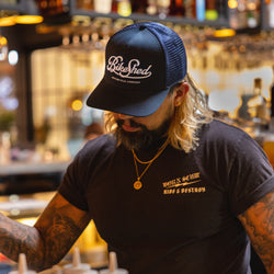 Bar staff member making a drink wearing our BSMC Motorcycle Garage Baseball Hat - Navy/White