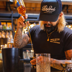 Bar staff member making a drink wearing our BSMC Motorcycle Garage Baseball Hat - Navy/White