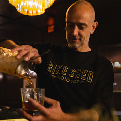Bar staff member make a cocktail wearing our BSMC Deco Motorcycle Sweatshirt - Black/Gold