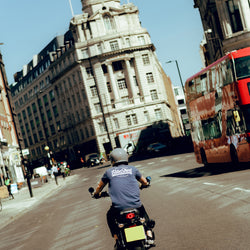 Steve riding past a London bus while wearing our BSMC Company Logo T-Shirt - Navy