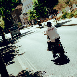 James riding his Harley in the sun wearing our Bike Shed Moto Co. Company T-Shirt - Off White
