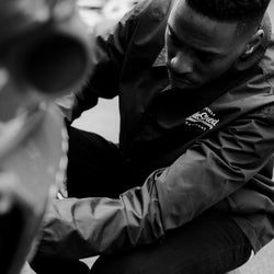 Model inspecting his bike wearing BSMC Company Coach Motorcycle Jacket - Black