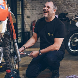 Dan working on his bike while wearing our Motorcycle BSMC ESTD. Pocket T Shirt - Black & Gold