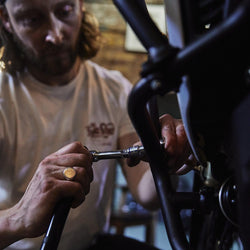 Gareth working on his bike while wearing our Bike Shed Motorcycle Company Graphic Handmade T Shirt - Cream