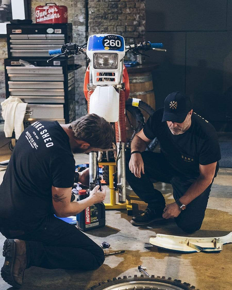 Dan working on his bike wearing our Motorcycle embroidered logo baseball hat - Black & Gold