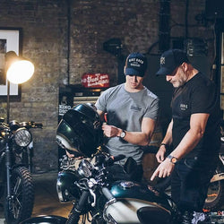 Dan wearing our Motorcycle embroidered logo baseball hat - Black & Gold while looking at Harry's bike