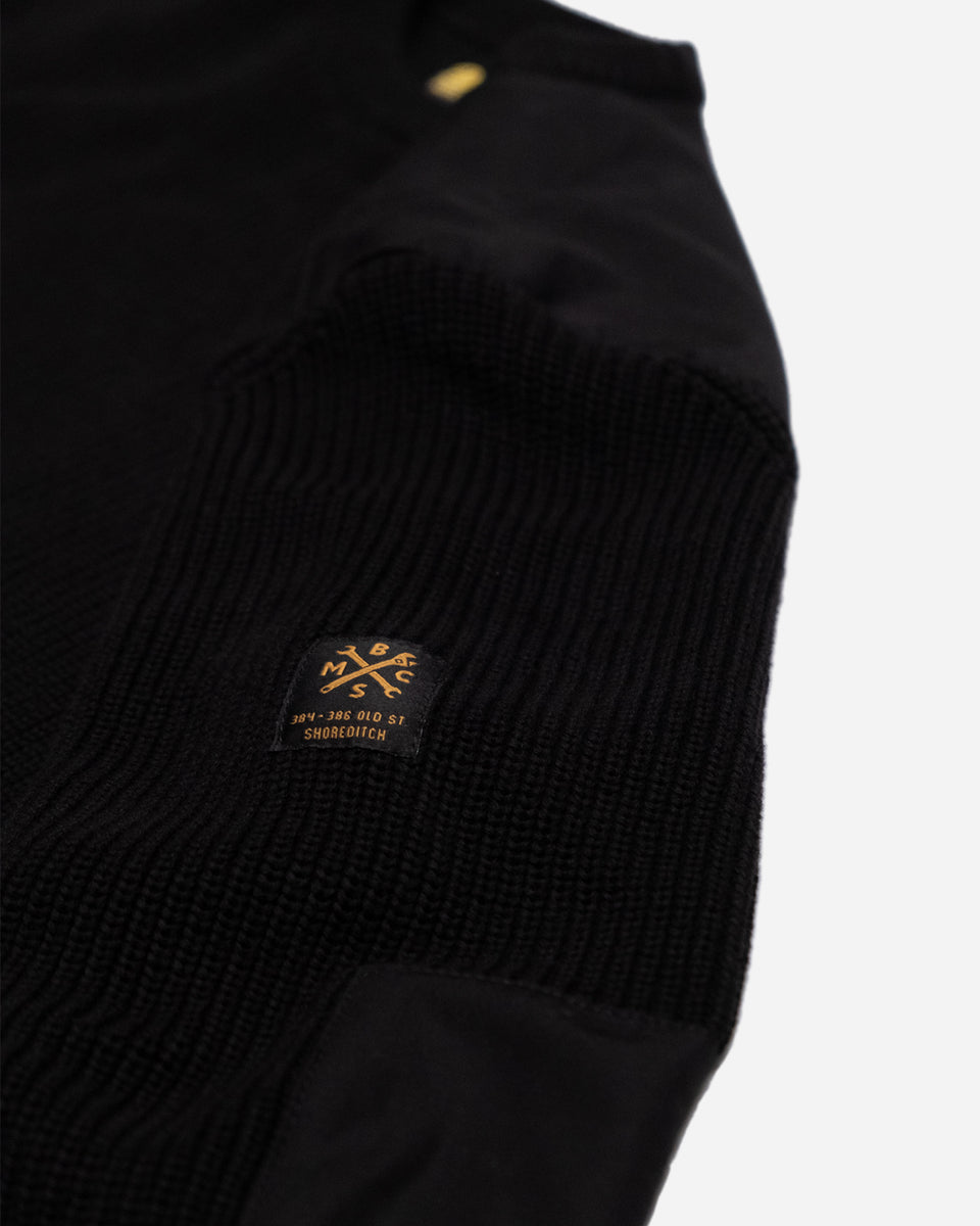 A black knit crew neck sweater with the Bike Shed Moto Co. brand label visible on the lower left side.