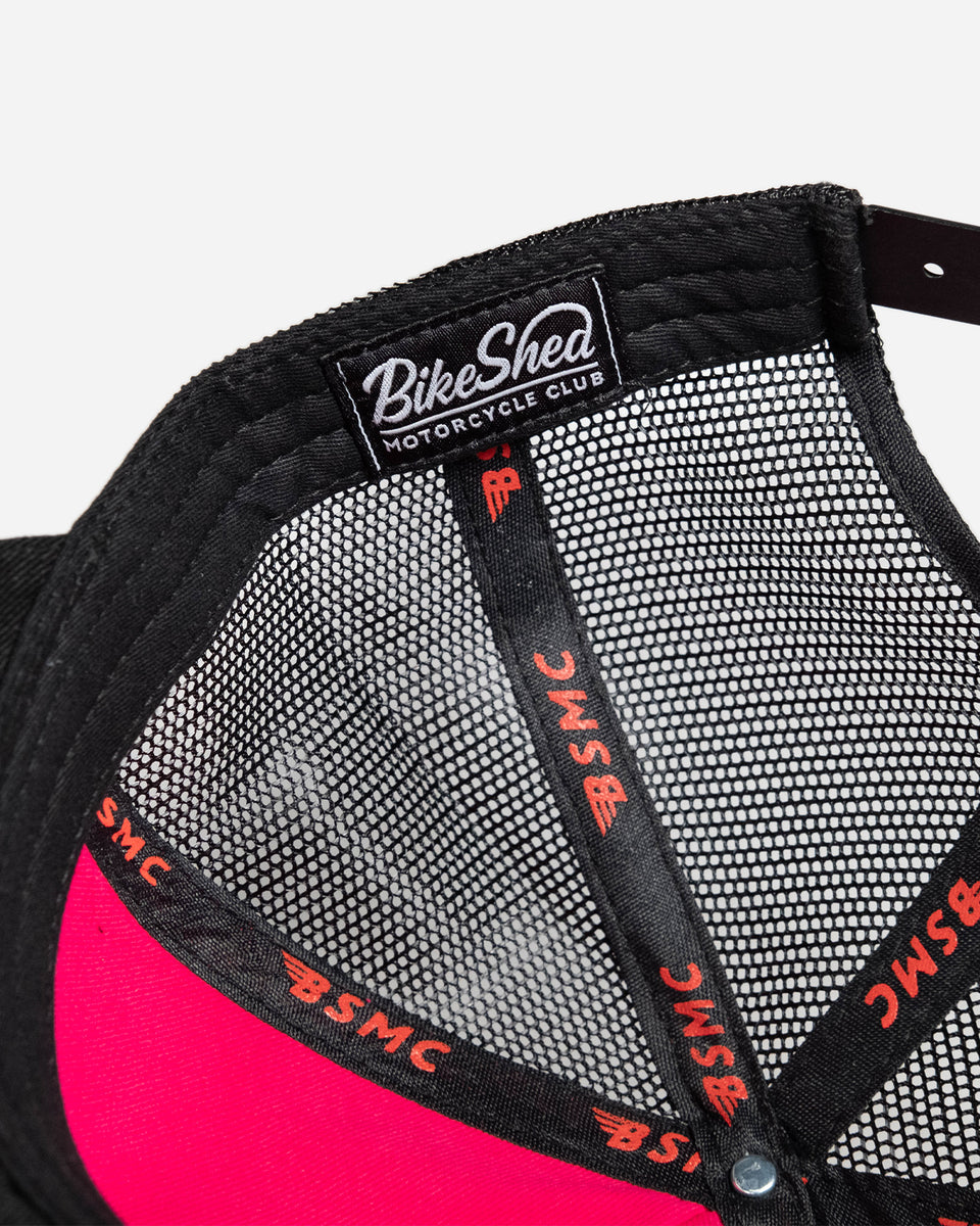 A black snapback baseball hat with a colorful patch on the front featuring a cartoonish motorcycle skull and bike shed logo - interior detail