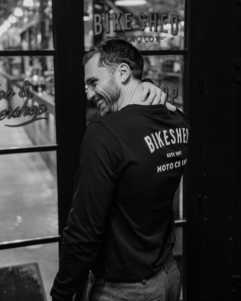Model wearing Bike Shed Moto Co ESTD Black Longsleeve in the Bike Shed London Restaurant 