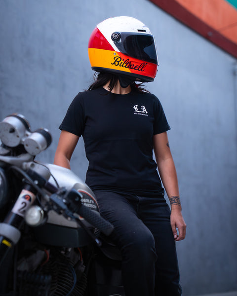 Model wearing Bike Shed Moto Co LA Rocker T-Shirt Black in front of a concrete back drop with a motorcycle 