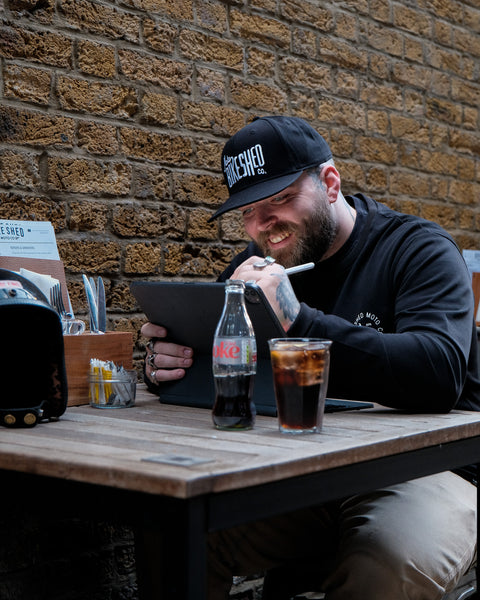 A black snapback baseball hat with 'Bike Shed Moto Co.' logo embroidered on the front.