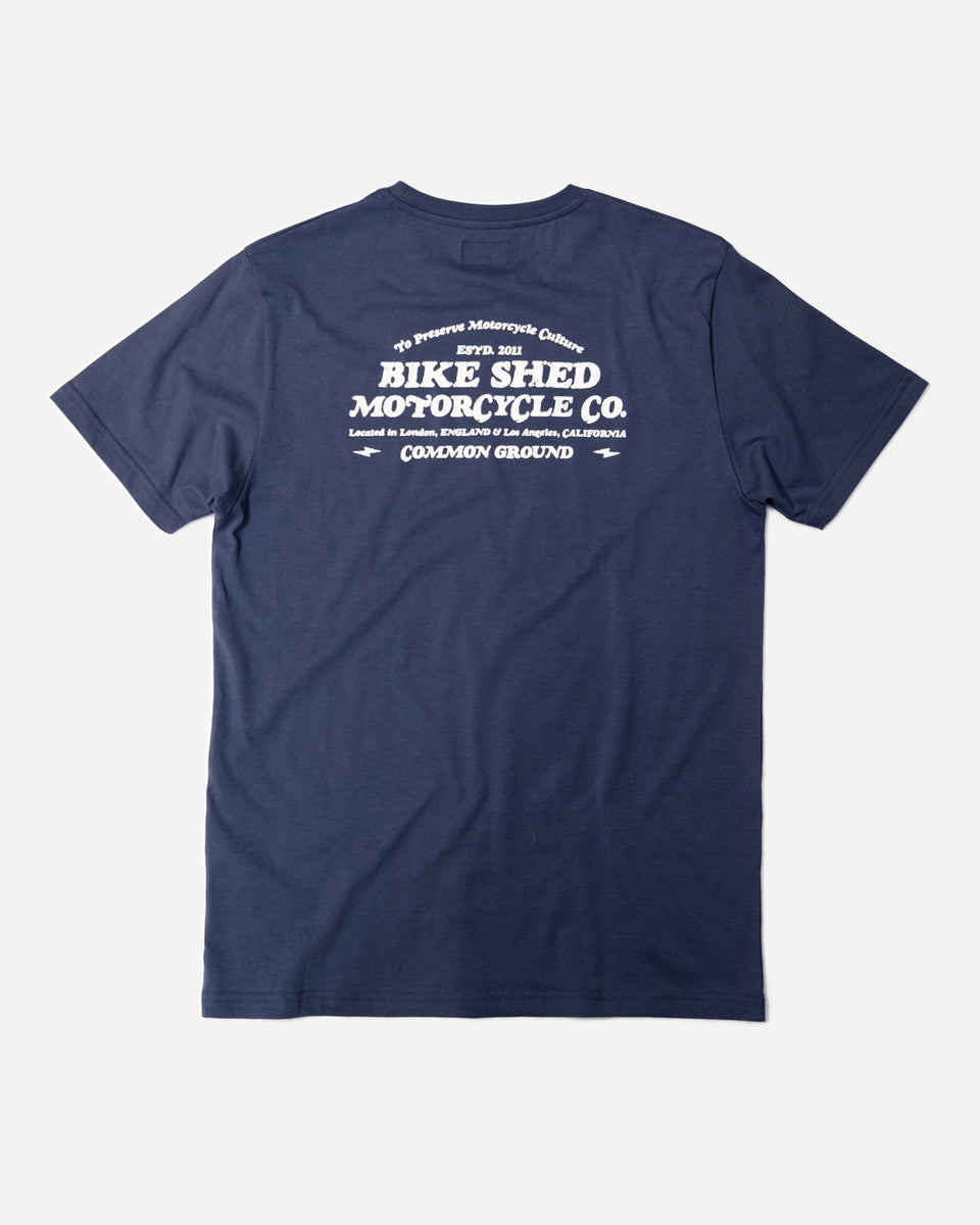 A navy-colored T-shirt with 'BIKE SHED MOTORCYCLE CO. COMMON GROUND' printed on the back.