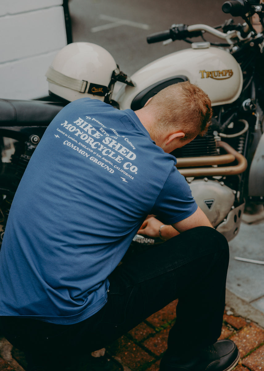 A navy-colored T-shirt with 'BIKE SHED MOTORCYCLE CO. COMMON GROUND' printed on the back.