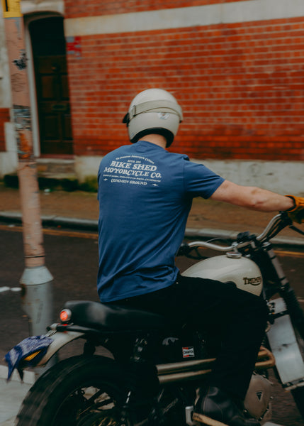 A navy-colored T-shirt with 'BIKE SHED MOTORCYCLE CO. COMMON GROUND' printed on the back.
