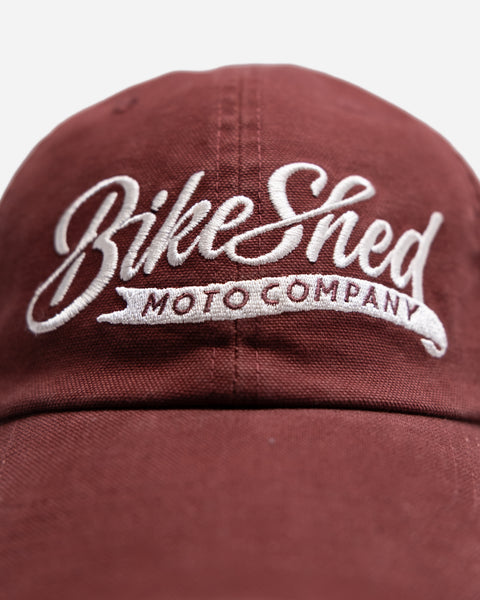 Red cap studio shot with 'Bike Shop Moto Company' logo on a white background