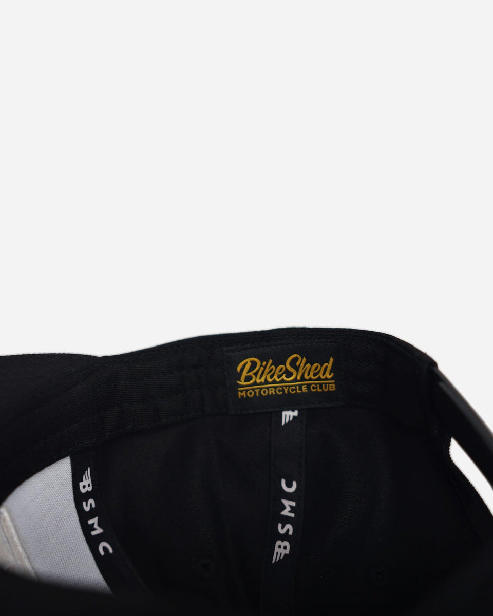 A black snapback baseball hat with 'Bike Shed Moto Co.' logo inner detail