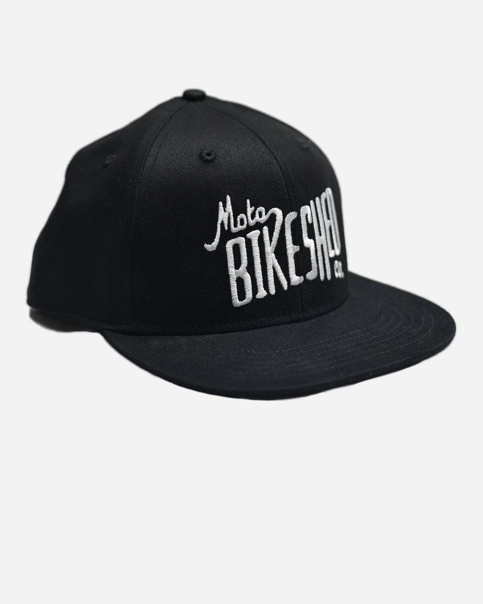 A black snapback baseball hat with 'Bike Shed Moto Co.' logo embroidered on the front.