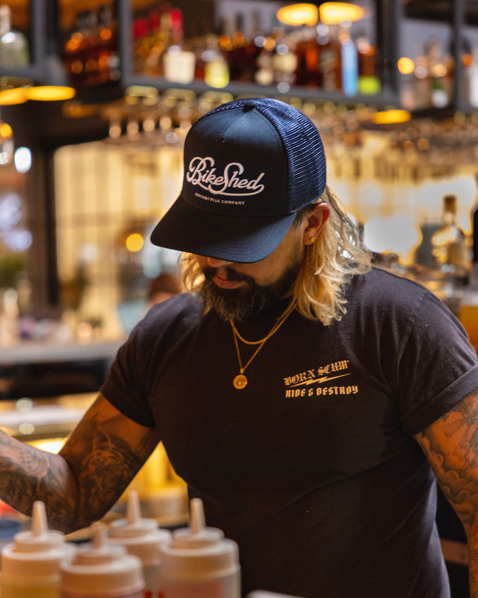 Bar staff member making a drink wearing our BSMC Motorcycle Garage Baseball Hat - Navy/White