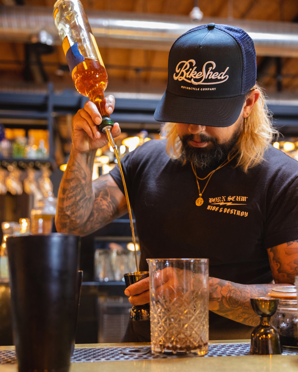 Bar staff member making a drink wearing our BSMC Motorcycle Garage Baseball Hat - Navy/White