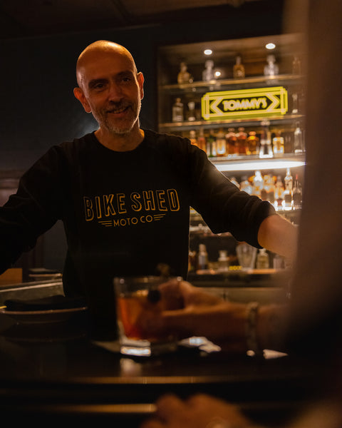Bar staff member chatting while wearing our BSMC Deco Motorcycle Sweatshirt - Black/Gold