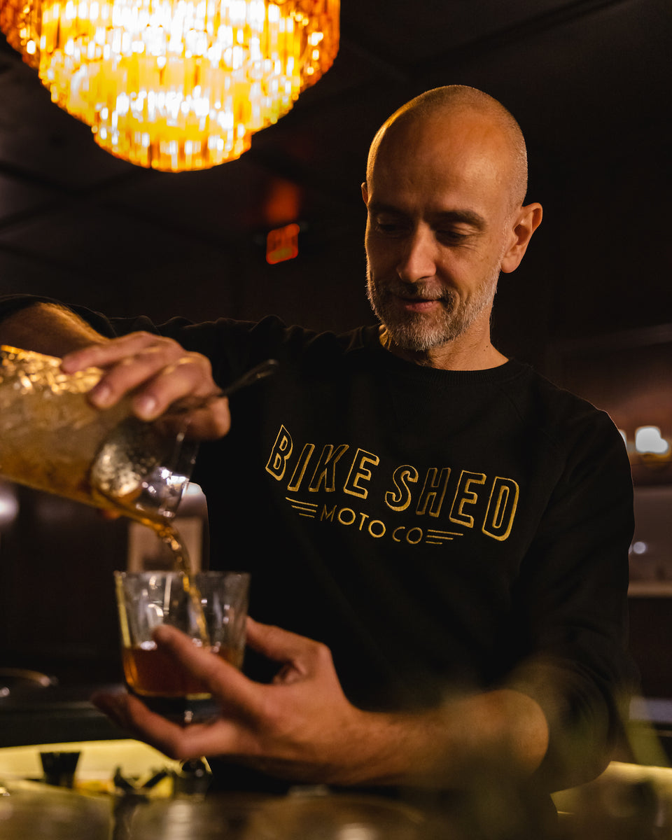 Bar staff member make a cocktail wearing our BSMC Deco Motorcycle Sweatshirt - Black/Gold