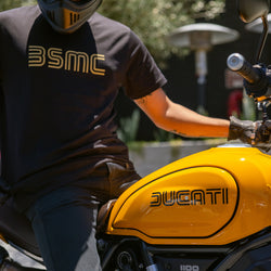 Model wearing BSMC '77 T shirt sitting on a Ducati Scrambler