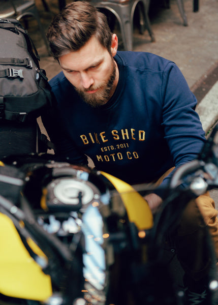 Alen inspecting his bike wearing our BSMC Moto Co. logo Sweatshirt - Navy/Mustard