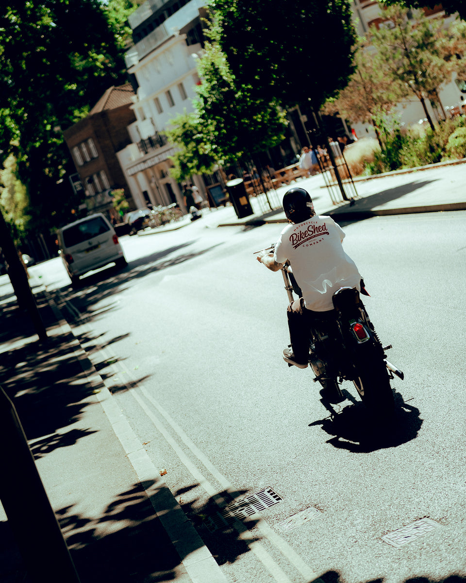 James riding his Harley in the sun wearing our Bike Shed Moto Co. Company T-Shirt - Off White