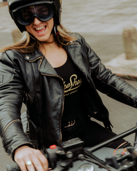 Model riding her bike wearing our Women's Motorcycle Garage Ribbed Tank Top - Black under her jacket