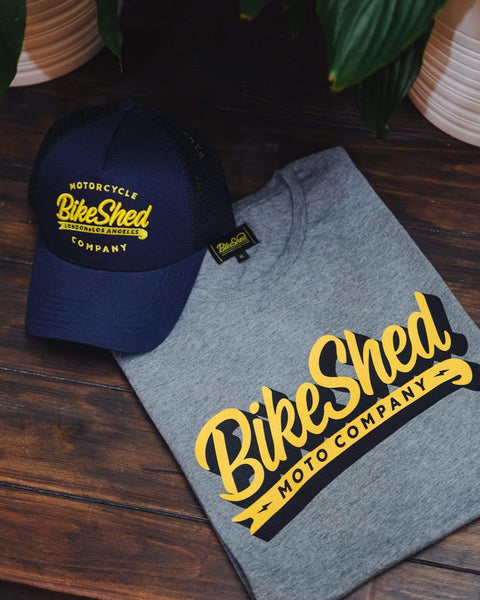 BSMC Classic Yellow Logo T-Shirt - Grey folded on a table with our Company Cap in Navy