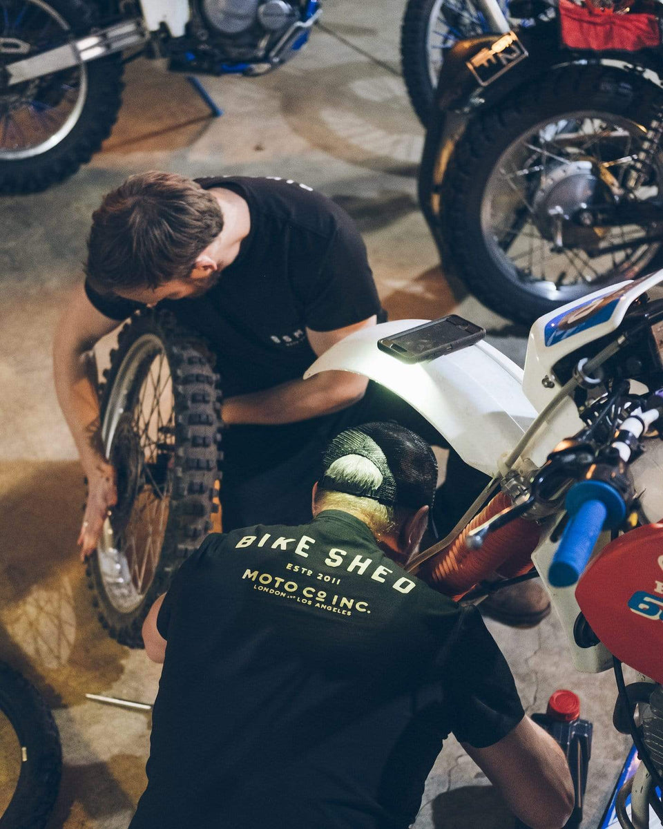 Gareth and Dan working on their bikes while wearing our Motorcycle BSMC ESTD. Pocket T Shirt - Black & Gold