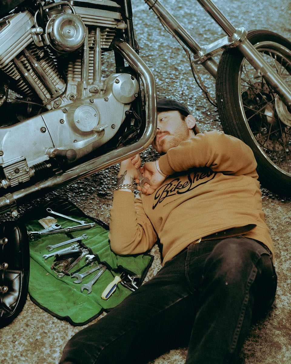 James working on his Harley while wearing our BSMC Motorcycle Garage Sweatshirt - Tan/Black