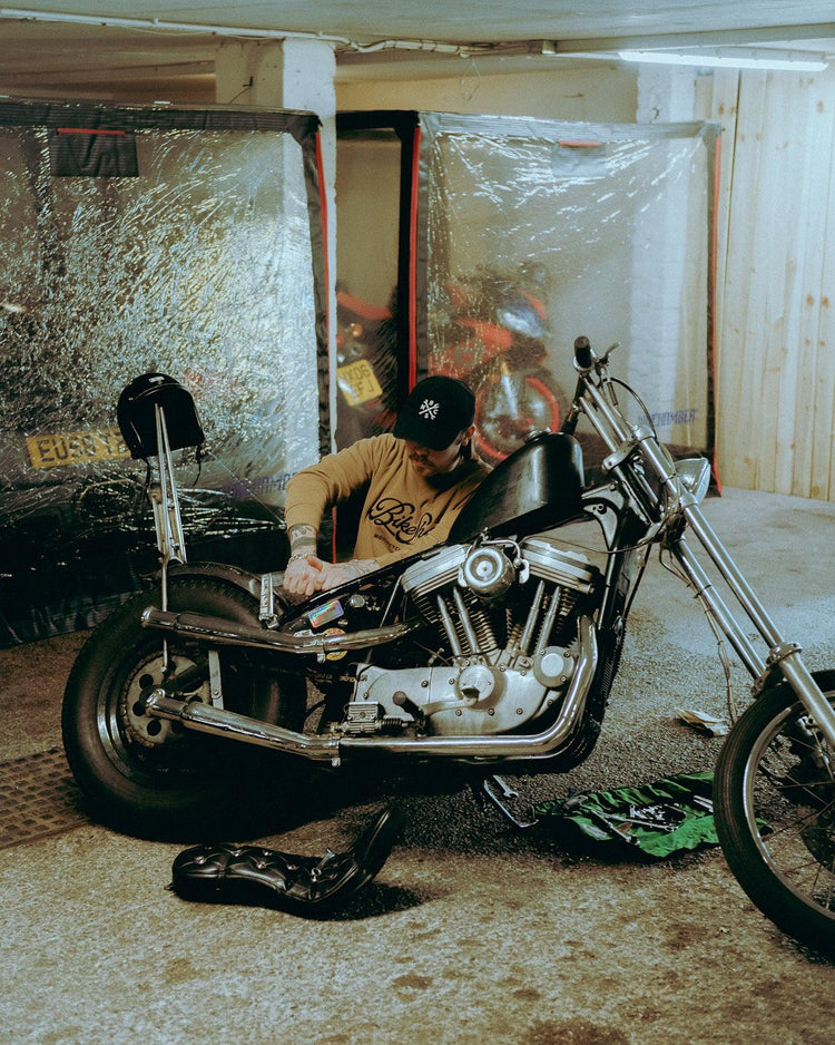 James working on his Harley while wearing our BSMC Garage Sweat - Tan/Black