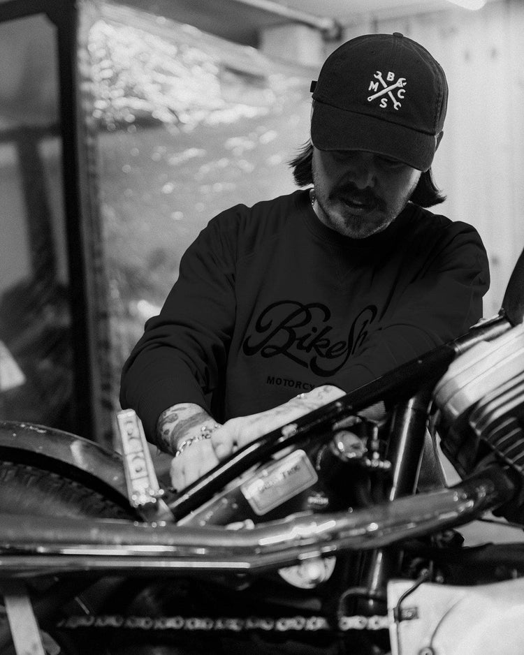 James wearing our BSMC Garage Sweat - Washed Black while working on his bike