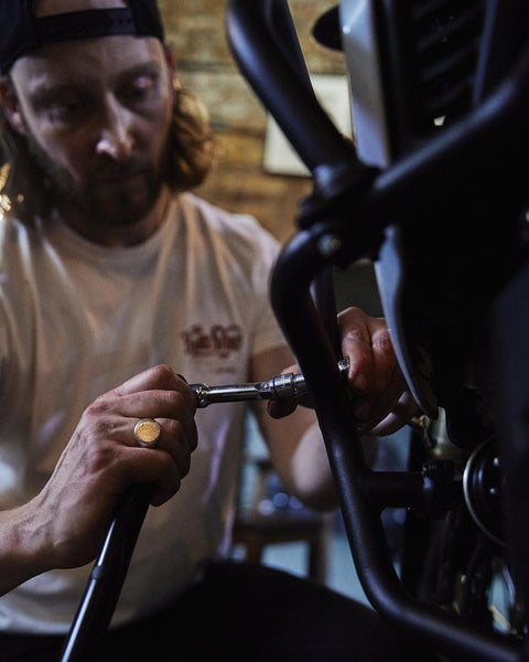 Gareth working on his bike while wearing our Bike Shed Motorcycle Company Graphic Handmade T Shirt - Cream