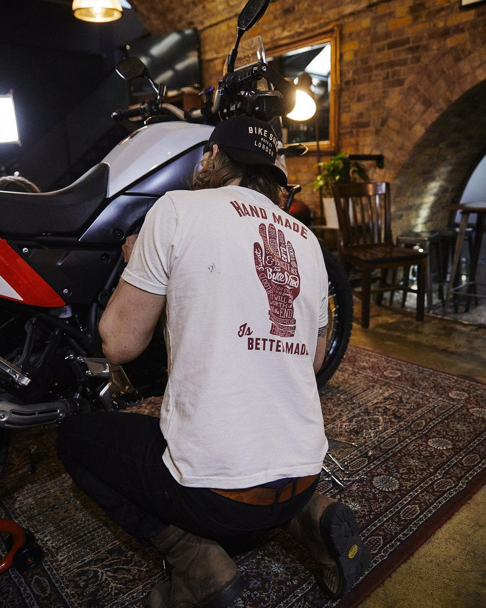 Gareth working on his bike while wearing our Bike Shed Motorcycle Company Graphic Handmade T Shirt - Cream, back