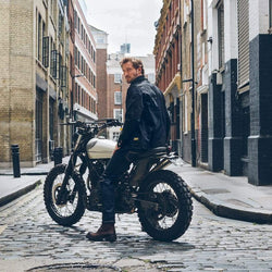 Model sitting on his bike wearing our BSMC Protective - Road Jean - Raw Indigo