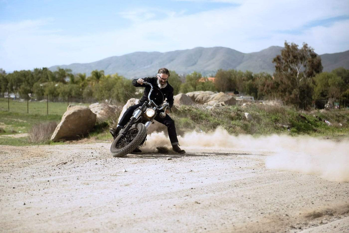 Model kicking up dust on his Harley while wearing our Motorcycle Resistant - BSR01 Jeans - Raw Indigo