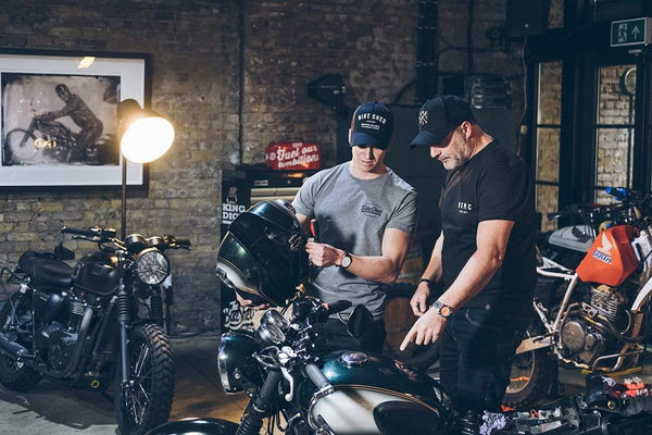 Dan wearing our Motorcycle embroidered logo baseball hat - Black & Gold while looking at Harry's bike
