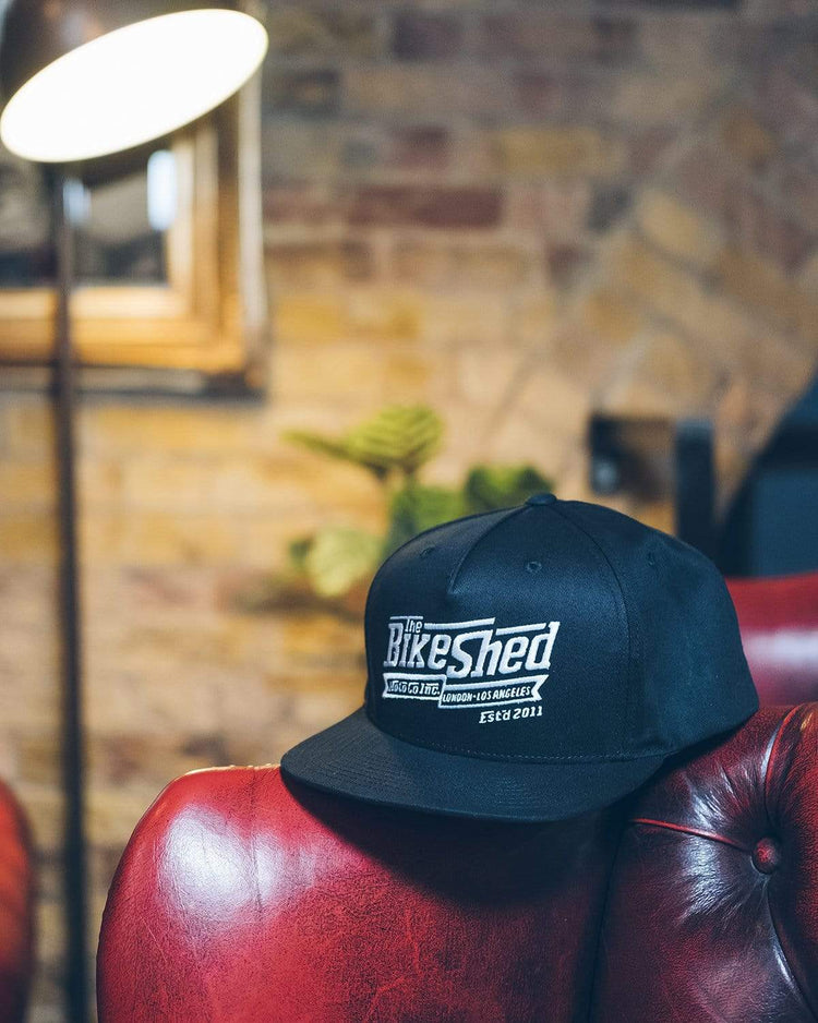 BSMC Steps Snapback - Black, resting on one of our Chesterfield sofas