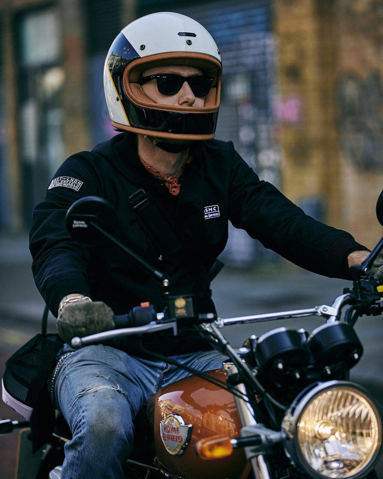 Kane wearing our BSMC x Royal Enfield Bomber Jacket - Black while riding a Royal Enfield 
