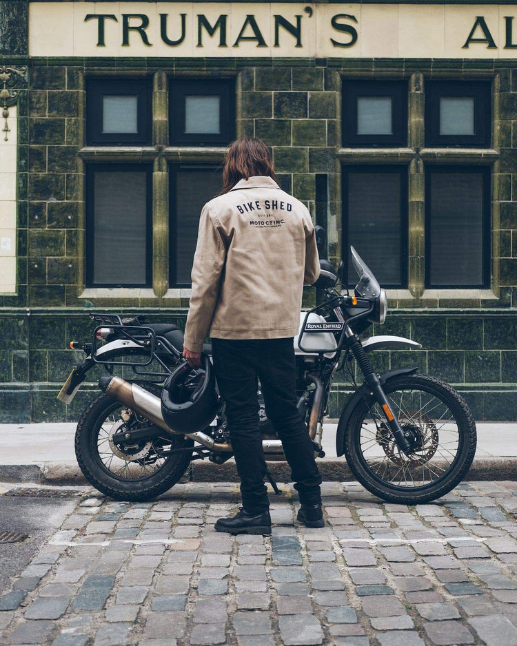 Dan wearing our BSMC ESTD. Canvas Jacket - Sand next to a Royal Enfield
